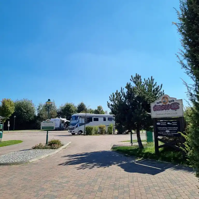 Wohnmobilhafen und Kurzzeit-Stellplatz beim Südsee-Camp in Wietzendorf Luftaufnahme des Südsee-Camps mit dem zentralen Badesee, dem Strandbereich und dem Wohnmobilstellplatz vor dem Campingplatz im Vordergrund. Im unteren Bildbereich sind zahlreiche Wohnmobile auf dem separaten Stellplatz zu sehen. Dahinter liegt der Campingplatz mit vielen Parzellen sowie das auffällige Schwimmbad mit einem großen Glasdach.