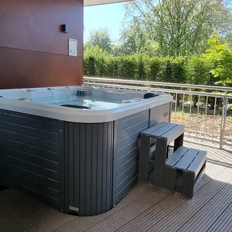 Whirlpool mit Einstiegstreppe auf der Dachterrasse eines Privatbads im Südsee-Camp, umgeben von Natur und Sichtschutz.