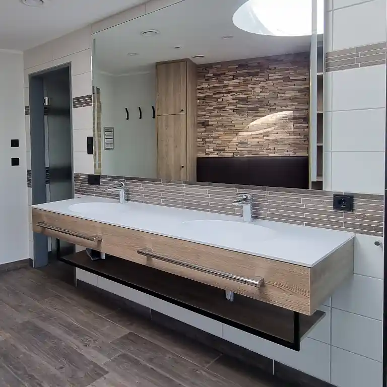 Modern ausgestattetes Privatbad im Waschhaus 4 des Südsee-Camps mit zwei Waschbecken, großem Spiegel, eleganter Holzoptik und sichtbarer Tür zum separaten WC.