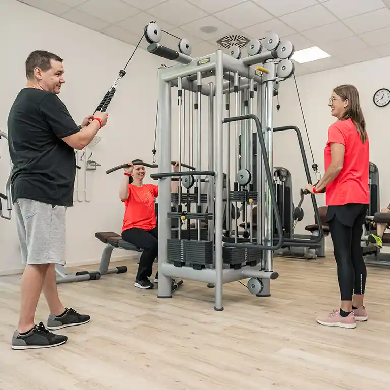 Drei Personen trainieren an verschiedenen Sportgeräten