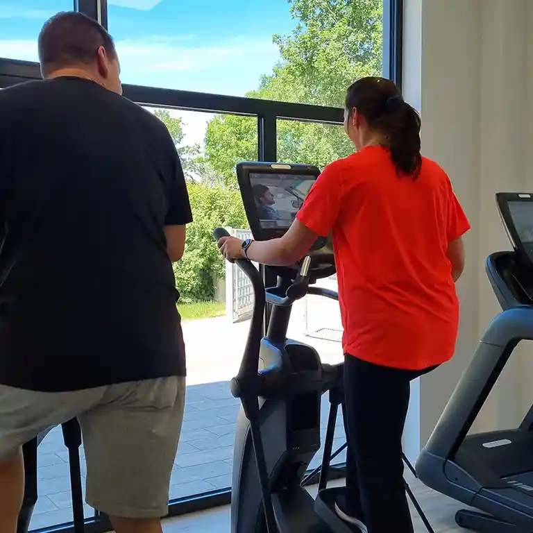 zwei Personen trainieren an Fitnessgeräten