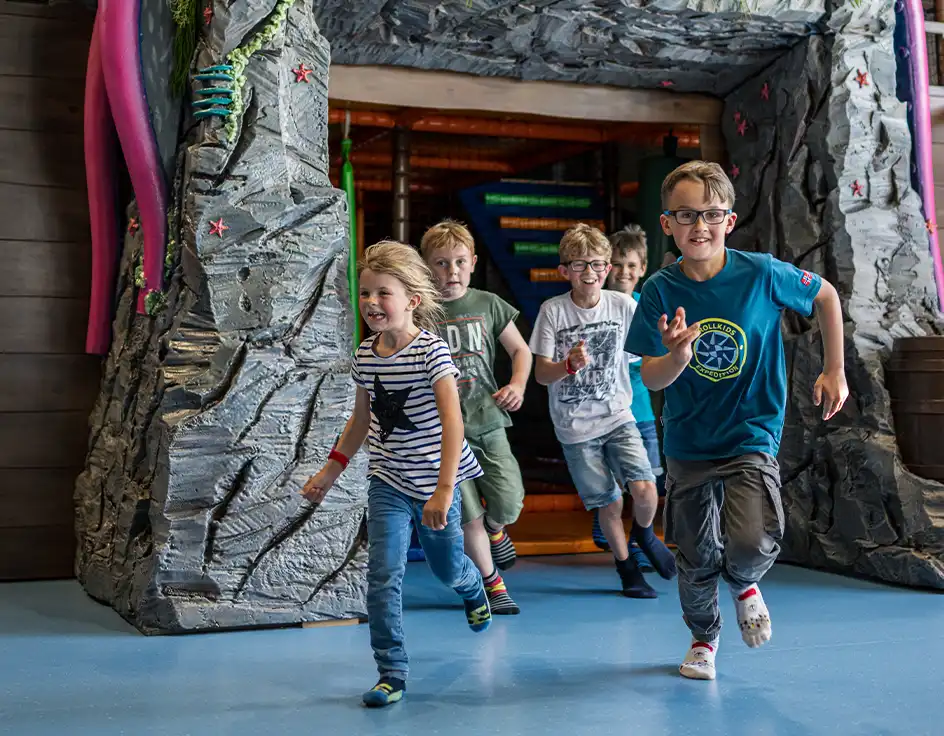 Freizeitangebot im Südsee-Camp: Kinder rennen lachend aus einem thematisch gestalteten Indoor-Spielbereich im Südsee-Camp – Spaß, Bewegung und Abenteuer für die ganze Familie.