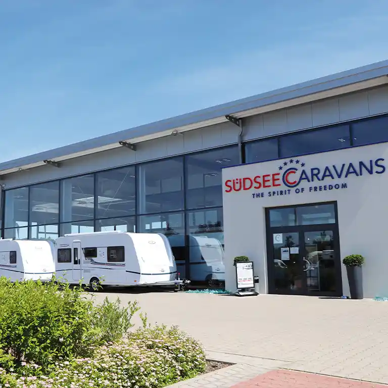 Südsee-Caravans: Moderner Showroom mit großen Glasfronten und mehreren ausgestellten Wohnwagen auf dem Vorplatz – Caravan-Erlebniswelt in Wietzendorf.