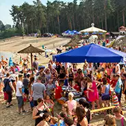 Sommerfest feiernde Menschen am Strand unter Sonnenschirmen