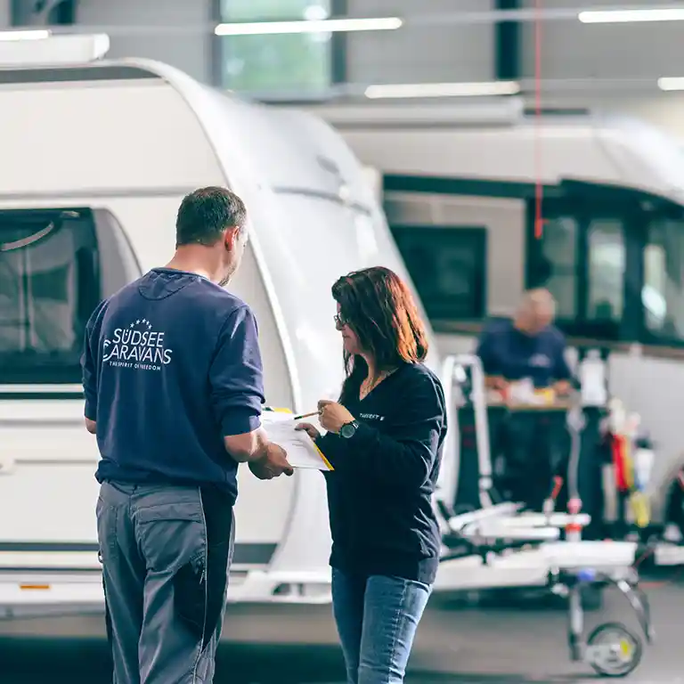 Zwei Personen vor einem Wohnwagen