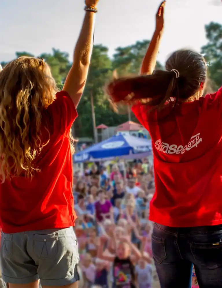 buntes Freizeit-Programm für alle! Animateurinnen auf der Bühne vor jubelndem Publikum beim Kinderprogramm