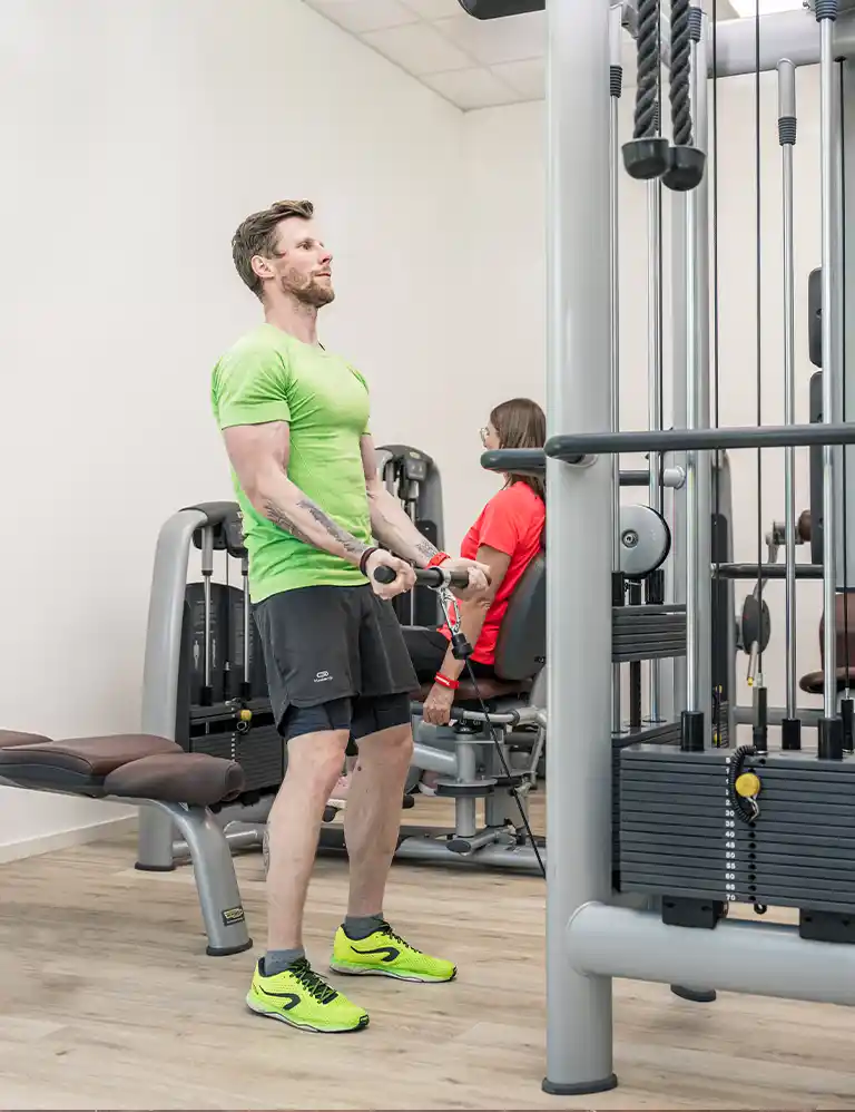 Fitnessraum entdecken! Zwei Personen trainieren an modernen Kraftgeräten im Fitnessraum