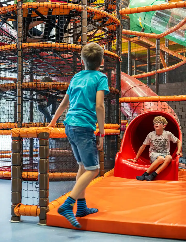 kommt spielen! Kinder im bunten Kletter- und Rutschbereich des Indoor-Spielplatzes